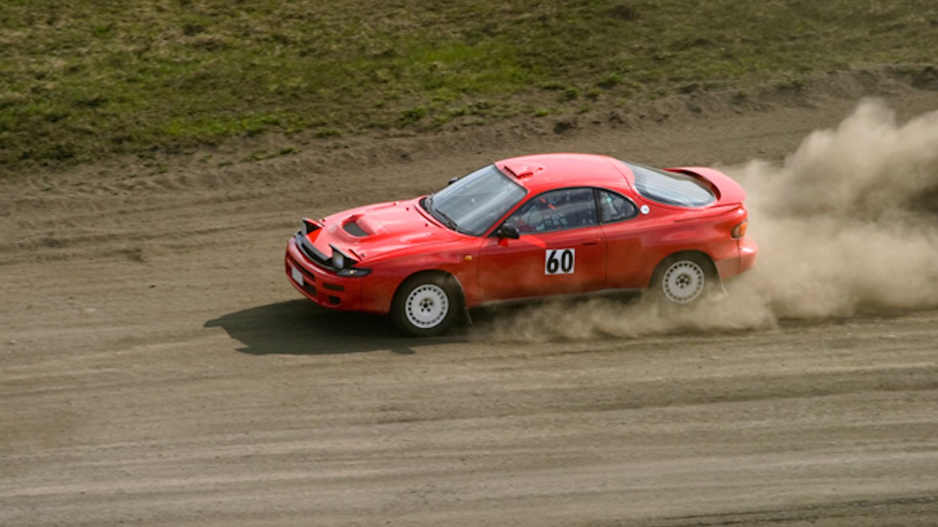 A Person Driving A Race Car On A Dirt Track